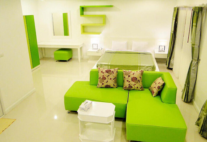 Sansuk Sauna Guesthouse room. Adults-only hotel with pool and sauna. Green couch, bed, and decor in this cheap gay hotel.