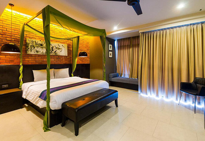 The Tama Hotel, Krabi, room. Cheap, gay-friendly hotel with pool. Four-poster bed, brick wall, bench, curtains. Gay travel advice.