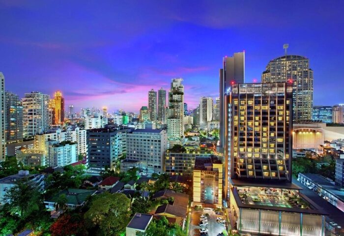 Bangkok skyline view from DoubleTree by Hilton Hotel Sukhumvit. Cheap, gay-friendly hotel with rooftop pool at dusk. Thailand travel.