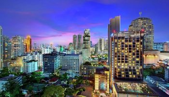 Bangkok skyline view from DoubleTree by Hilton Hotel Sukhumvit. Cheap, gay-friendly hotel with rooftop pool at dusk. Thailand travel.