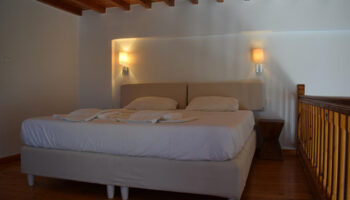M for Mykonos hotel room. Cheap gay hotel in Mykonos Town near Little Venice. Double bed, wooden floor and ceiling. Gay travel advice.