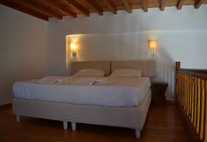 M for Mykonos hotel room. Cheap gay hotel in Mykonos Town near Little Venice. Double bed, wooden floor and ceiling. Gay travel advice.