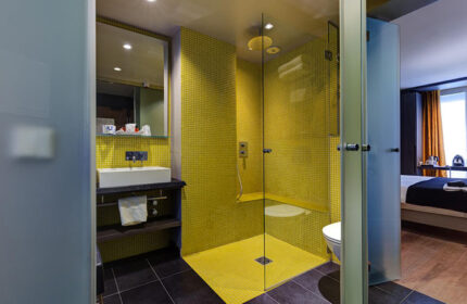 Hotel Elixir, a cheap gay hotel in Paris city center. Modern bathroom with yellow tile shower. Gay travel advice for Paris hotels.