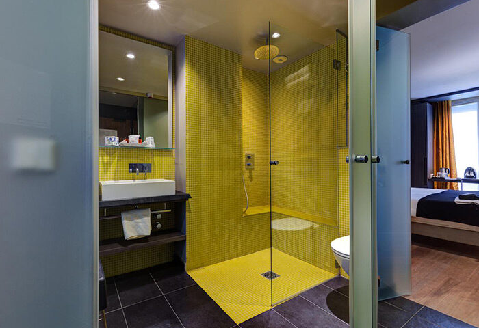 Hotel Elixir, a cheap gay hotel in Paris city center. Modern bathroom with yellow tile shower. Gay travel advice for Paris hotels.