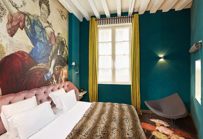 Hotel du Petit Moulin room. Gay-friendly Paris hotel in Le Marais. Luxurious bed, colorful decor, and unique design. Cheap gay hotel option.