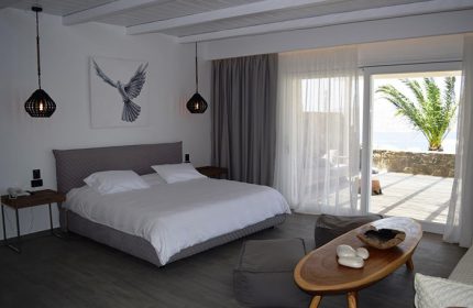Hermes Mykonos Hotel room interior. Gay-friendly hotel in Mykonos Town, Greece. Bedroom with balcony, sea view, and modern decor. Mykonos gayborhood.