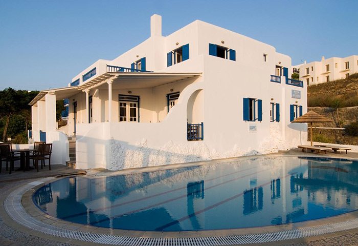 Marisso Hotel, a cheap gay hotel in Mykonos Town. Pool view of the gay-friendly hotel near gay bars. White building with blue accents.