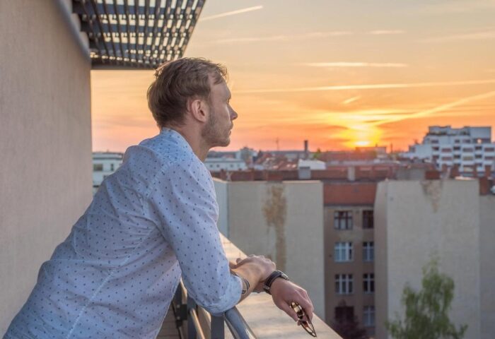 Hotel Ku'Damm 101: Gay man on balcony at sunset. City Center hotel near gay bars in Berlin. Cheap gay hotels for gay travel advice.