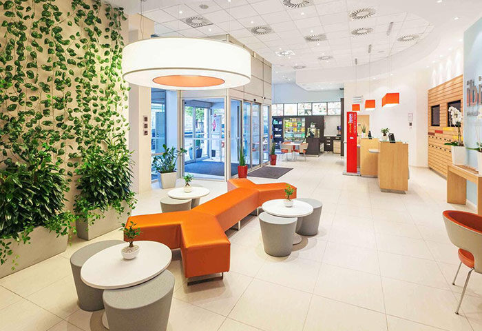 Ibis Praha Wenceslas Square Hotel lobby. Modern design with plants, orange seating, and reception. Gay-friendly hotel near Prague nightlife.