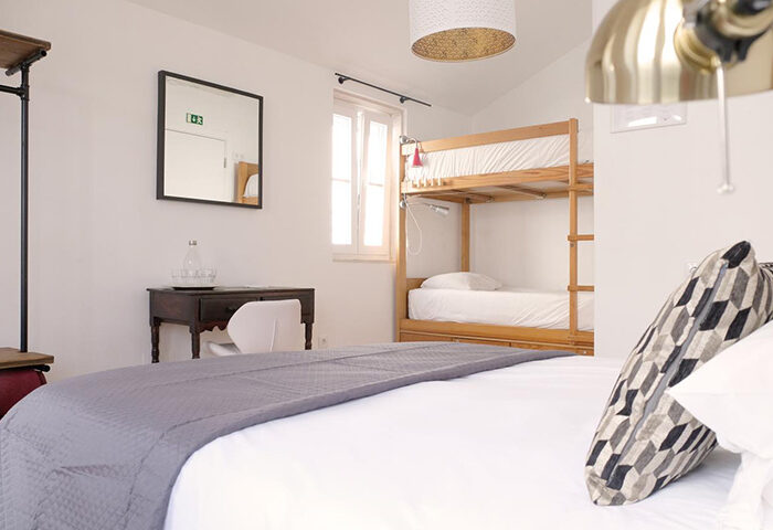 Lisbon Poets Inn Hostel room. Cheap gay hotels in Lisbon city center. Bunk beds, desk, and modern decor in a bright, clean space.