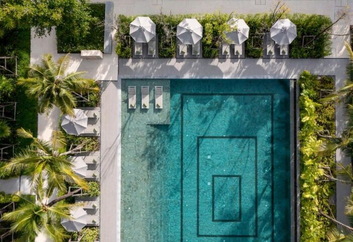 Melia Phuket Mai Khao outdoor pool. Aerial view of luxury gay-friendly beach resort with umbrellas and palm trees. Thailand travel.
