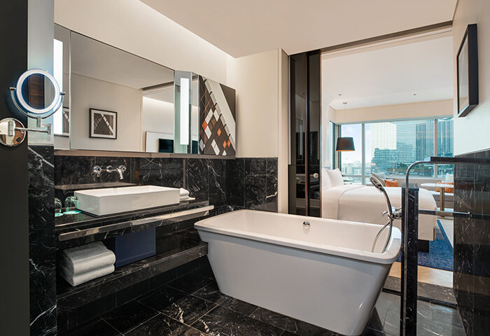 Le Méridien Bangkok hotel bathroom. Luxury bathtub, marble surfaces, and view into the bedroom. Gay-friendly hotel in Bangkok's gay area.
