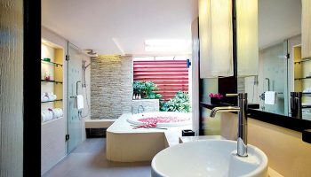 Chaweng Regent Beach Resort's luxury bathroom. Spa lovers' gay hotel in Koh Samui features a tub with petals and a modern shower.