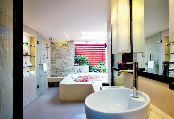 Chaweng Regent Beach Resort's luxury bathroom. Spa lovers' gay hotel in Koh Samui features a tub with petals and a modern shower.