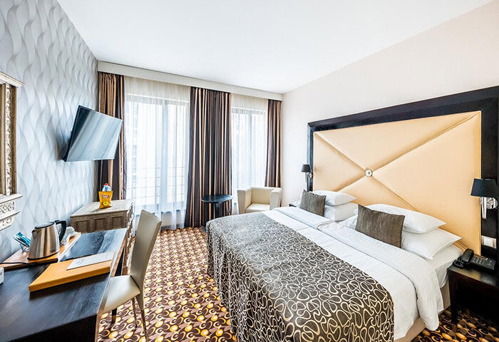 Grandior Hotel Prague room. Cheap luxury gay hotel in Prague Old Town with gym. Modern design, double bed, desk, chair, TV, and patterned carpet.