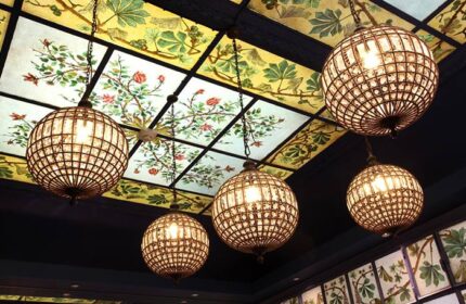 Ceiling detail at Little Palace Hotel, a cheap luxury gay hotel in Paris' Marais gayborhood. Globe lights hang from a floral stained glass ceiling.