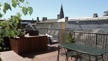Hotel Herman K by Brøchner Hotels rooftop garden in Nyhavn. Luxury gay hotel with a table and chairs, plants, and a view of the city.