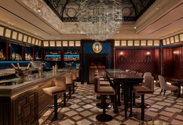 Interior of Great Scotland Yard Hotel, a cheap luxury gay hotel in London. Bar with stools, drinks, and a chandelier.