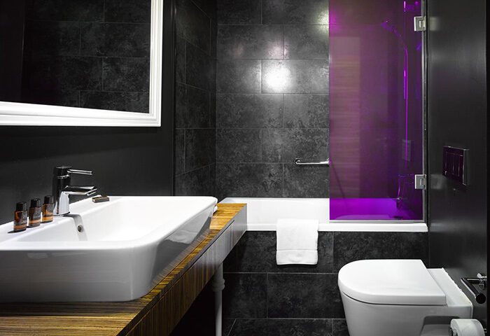 The Icon Hotel and Lounge bathroom. Cheap luxury gay hotel in Prague Old Town. Dark tile, modern sink, and purple-lit shower.