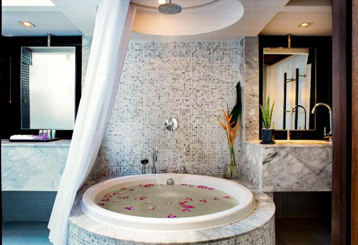 Luxury private pool villa at Centara Villas Phuket, a gay-friendly hotel. Bathroom with round tub, mosaic tiles, and flowers. Relaxing Phuket getaway.