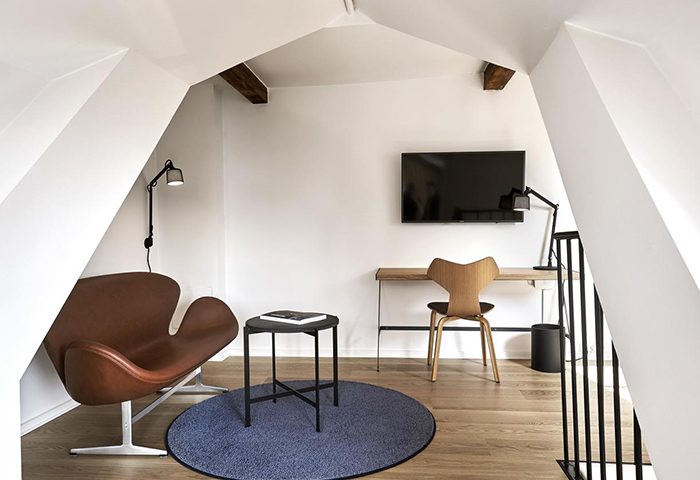 71 Nyhavn Hotel room interior. Luxury Copenhagen hotel near Vesterbro Gayborhood. Desk, chair, and stylish brown leather armchair.