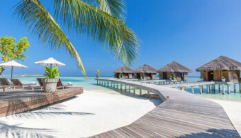LUX* South Ari Atoll, Maldives over-the-water beach resort. Tropical gay travel destination with bungalows and wooden walkways.