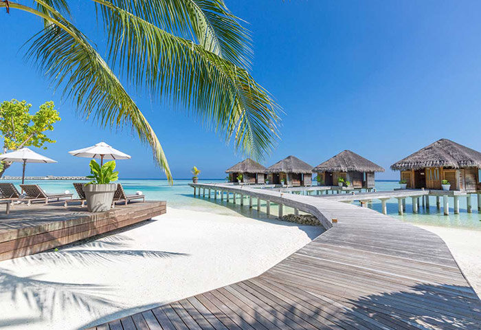LUX* South Ari Atoll, Maldives over-the-water beach resort. Tropical gay travel destination with bungalows and wooden walkways.