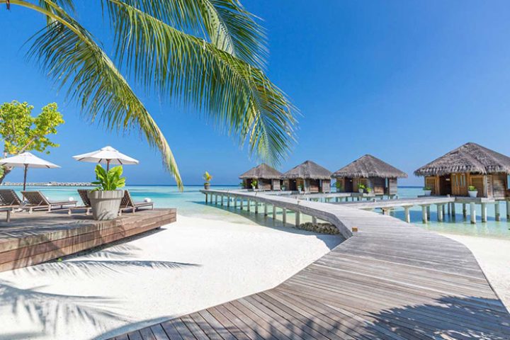 LUX* South Ari Atoll, Maldives over-the-water beach resort. Tropical gay travel destination with bungalows and wooden walkways.