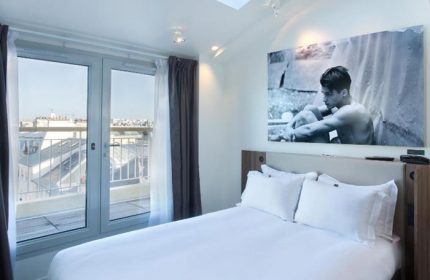 Hotel Jules & Jim, Paris. Modern room with a large window, city view, and a black and white photo of a man above the bed. Gay hotel.