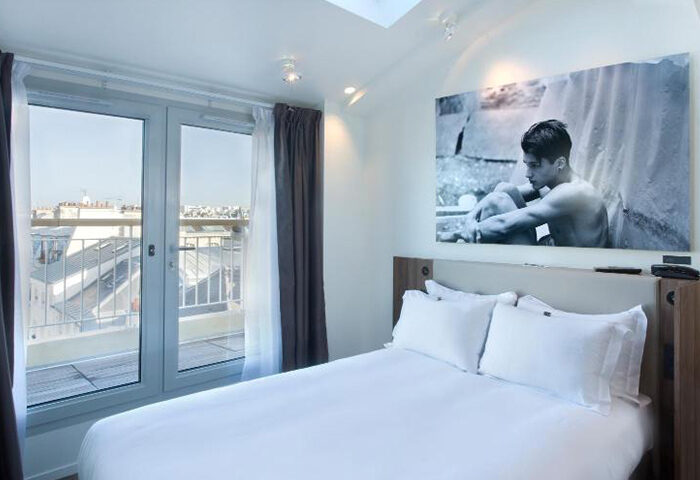 Hotel Jules & Jim, Paris. Modern room with a large window, city view, and a black and white photo of a man above the bed. Gay hotel.