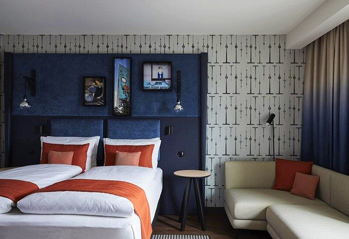 Hotel Indigo Berlin East Side Gallery room. Twin beds, blue headboard, art, and sofa. Popular gay hotel in Berlin. Cheap hotel deal.
