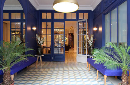 Little Palace Hotel, a gay-friendly hotel in Paris' Marais district. The entrance features blue walls, patterned floors, and stylish decor.