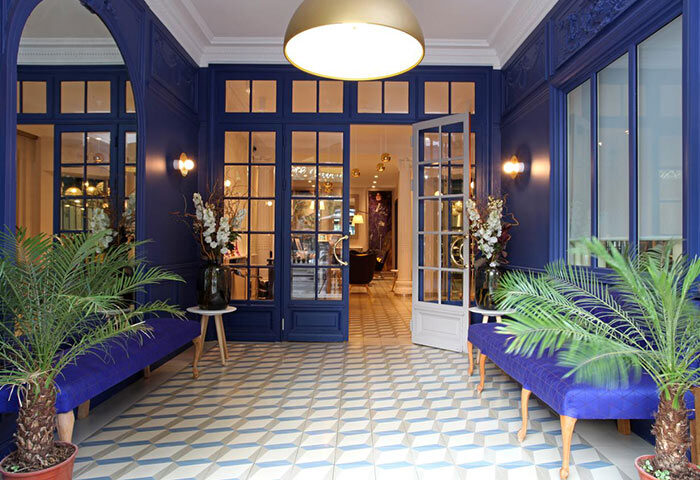 Little Palace Hotel, a gay-friendly hotel in Paris' Marais district. The entrance features blue walls, patterned floors, and stylish decor.