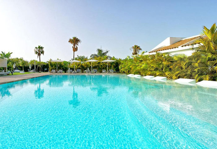 Seven Hotel Wellness, gay men only in Gran Canaria. Cheap price gay hotel with pools. Outdoor pool with palm trees and lounge chairs.