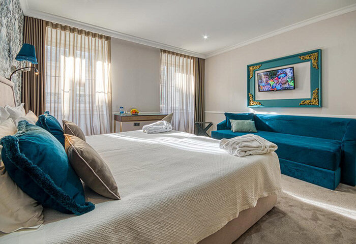 Hotel Borges Chiado room. Cheap price gay hotel in Lisbon's gayborhood. Bedroom with bed, blue couch, and TV. Gay travel advice.