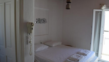 M for Mykonos: Cheap price gay hotel room in Mykonos Town (Chora) near Panagia Church. Simple, clean, white decor. Balcony access.