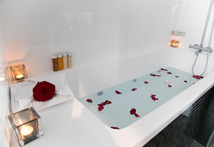 Bathtub with rose petals and candles at L'Empire Paris Hotel, a cheap-price gay hotel in Paris. Luxury gay travel experience.