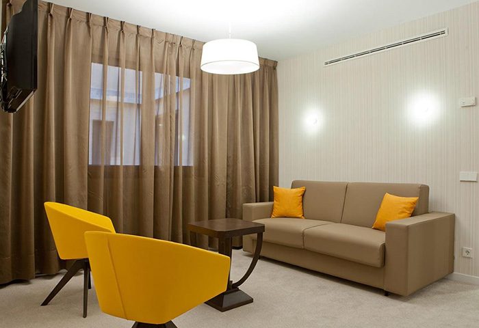 Hotel Liabeny gay-friendly room in Madrid's gayborhood. Cheap price room for 3 people on Gran Via. Modern design with sofa and yellow chairs.