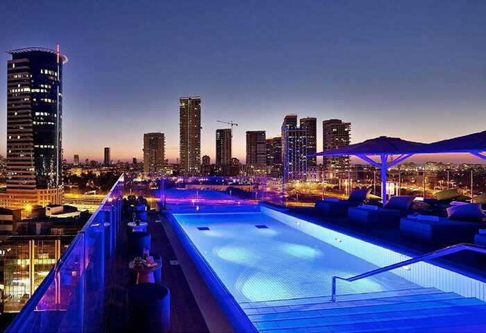 Hotel Indigo Tel Aviv Diamond District rooftop pool at night. Gay hotel in Tel Aviv city center with skyline view. Cheap price, great location.