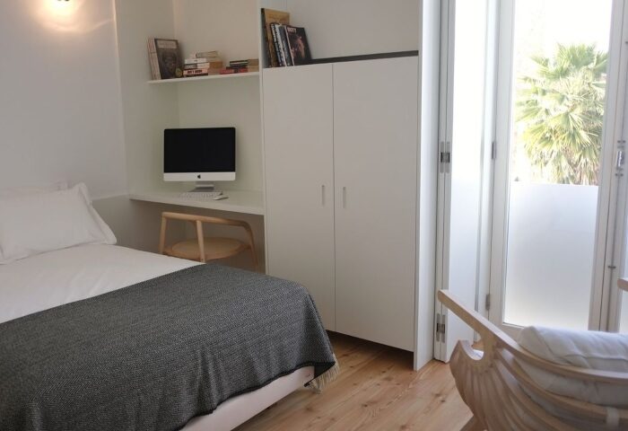 The Late Birds Lisbon gay hotel room. Minimalist design with bed, desk, computer, wardrobe, and balcony. Popular among gay travelers.