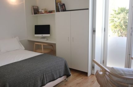 The Late Birds Lisbon gay hotel room. Minimalist design with bed, desk, computer, wardrobe, and balcony. Popular among gay travelers.