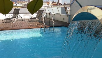 Ako Suites Hotel Barcelona rooftop pool. Cheap-price gay serviced apartment with sun loungers and waterfall feature.