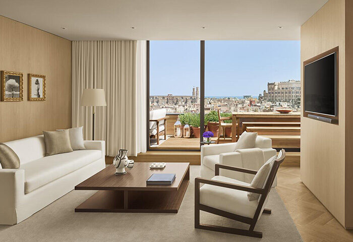 The Barcelona EDITION luxury hotel living room. City center view from balcony. Stylish, gay-friendly travel destination.