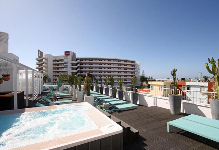 Gold Playa del Ingles Adults Only: Upscale gay hotel rooftop pool view. Hot tub, sun loungers, and cactus plants. Gran Canaria gay travel.