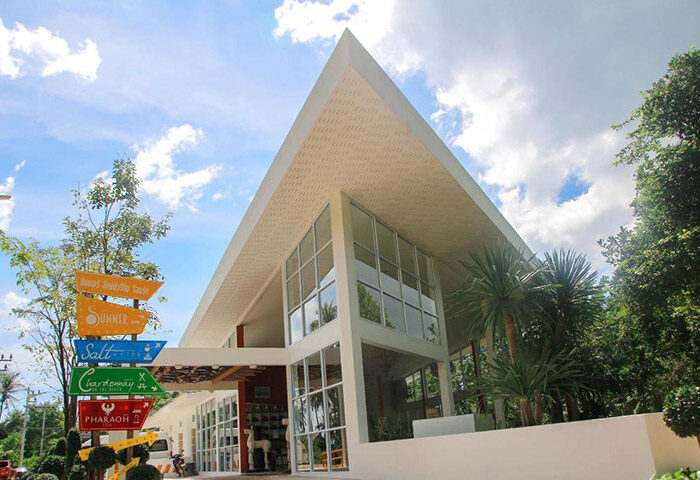 Koh Phangan Summer Luxury Beach Resort. Upscale gay hotel exterior with modern architecture, signpost, and tropical plants.