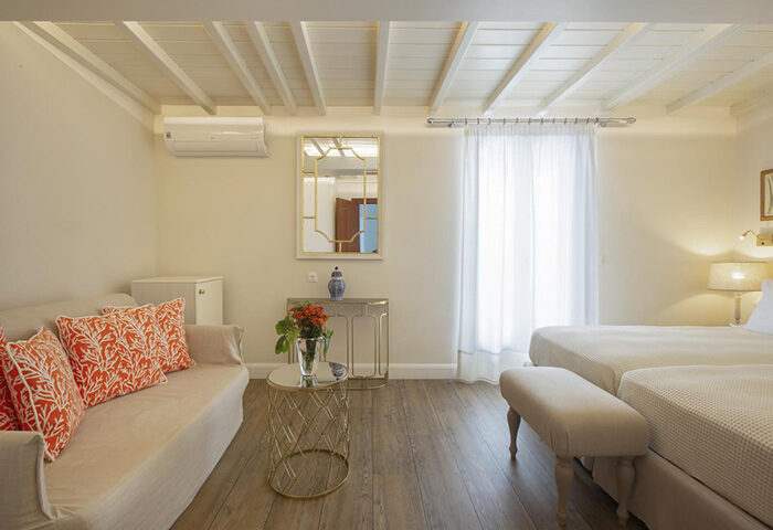 Despotiko Hotel, Mykonos Town: Upscale room interior. Two beds, couch with orange pillows. Gay-friendly hotel with swimming pool.