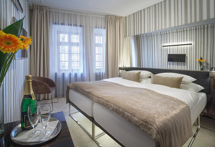 Hotel Clementin Old Town room. Upscale gay hotel in Prague city center. Champagne, flowers, and double bed. Striped wallpaper.