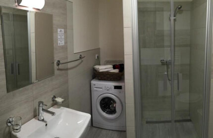 Hotel Residence Spalena apartment bathroom. Cheap Prague gayborhood lodging with washing machine, shower, sink, and mirror.