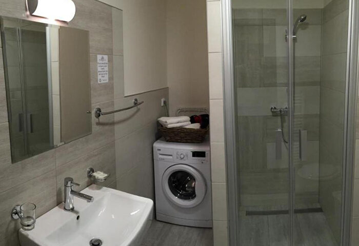 Hotel Residence Spalena apartment bathroom. Cheap Prague gayborhood lodging with washing machine, shower, sink, and mirror.