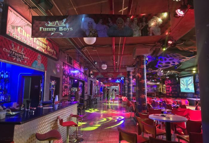 Chez Funny Boys gay bar in Gran Canaria. Interior view with bar, tables, stage, and drag queen imagery. Nightlife scene.